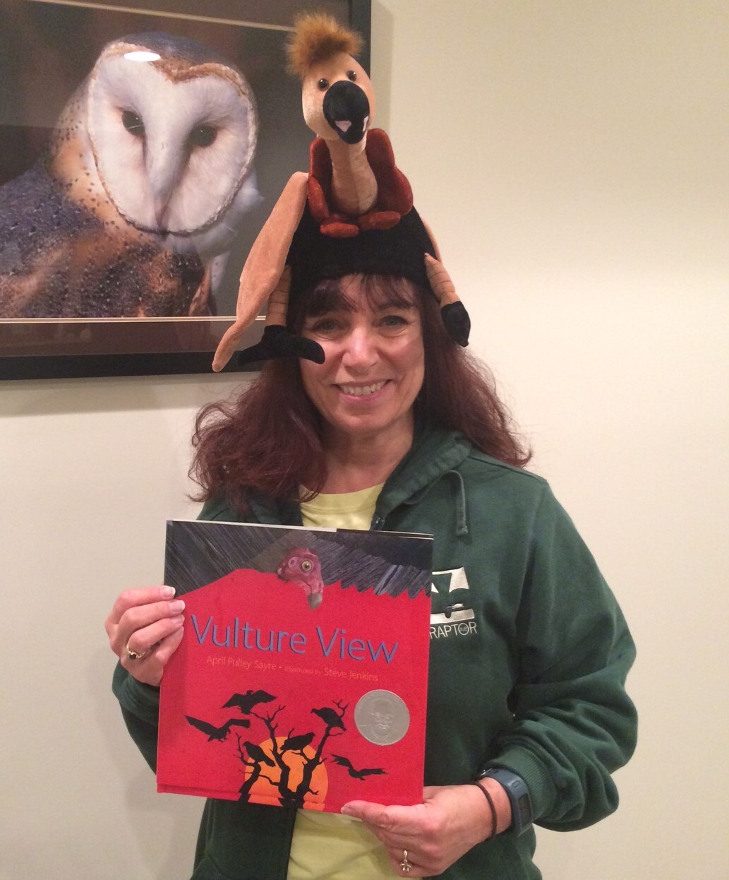 teacher with book wearing Vulture stuffed animal on head